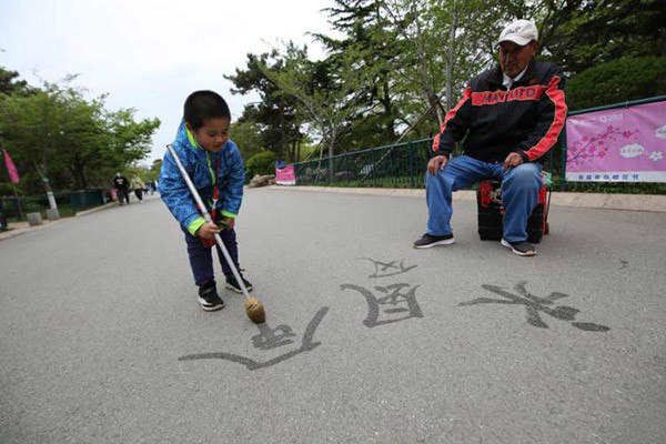 Old man practicing water calligraphy in the park inspired little "calligrapher" to learn the art
